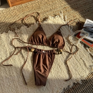 Close-up of coffee brown beaded halter bikini top and tie-side bottoms on a woven mat