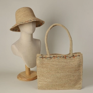Detail of raffia sun hat and tote bag featuring intricate floral embroidery and woven texture