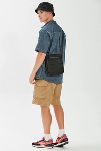 Men's black crossbody bag shown in a city boy style outfit with cargo shorts