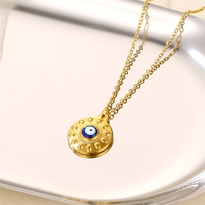 Evil eye pendant necklace in gold with blue enamel and sunburst details on a tray