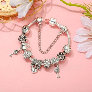 Detail of silver beaded charm bracelet featuring heart key, bow, and crystal pave charms