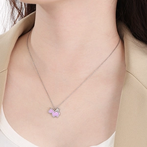 Dettaglio di un ciondolo a forma di unicorno rosa su una catena d'argento su modella
