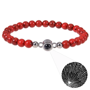 Detail of red beaded bracelet with projection stone showing I Love You in 100 languages