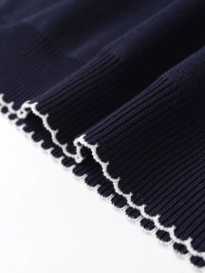Detailed close-up of navy rib-knit fabric with white wavy contrast edge stitching