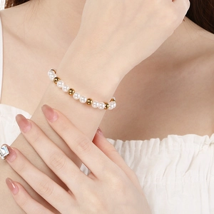 Elegantes Perlenarmband mit weißen Perlen und goldenen Metallperlen am Handgelenk