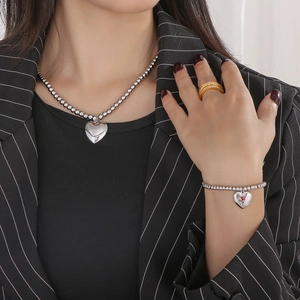Detailed shot of silver beaded chain necklace and heart pendant set on a model