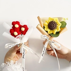 Close-up of hand-knitted mini sunflower and red flower bouquets in gift wrapping