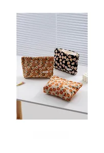 Detailed view of floral corduroy makeup bags in brown, black, and beige textures