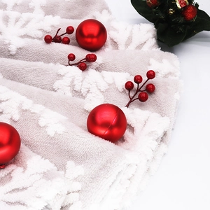 Close-up of white snowflake pattern on plush faux fur Christmas tree skirt with red decor