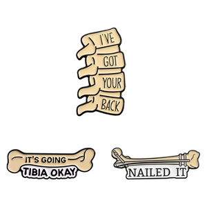 Three creative skeletal enamel pins with humorous bone puns on white background