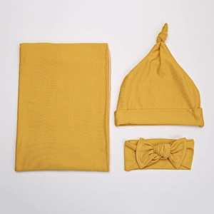 Close-up of mustard yellow ribbed knit baby swaddle set with headband and knotted hat