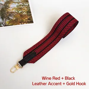 Detail of burgundy and black geometric woven wide bag strap with gold metal hooks
