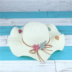 Detail of wide brim straw hat with colorful cloth flowers and brown leather band decoration