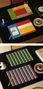 Detail view of colorful geometric art placemats on a luxury dark table setting