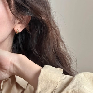 Primer plano de pendientes de aro dorados minimalistas lucidos por una modelo