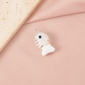 Detailed view of a white handcrafted glass fishbone pendant with blue eyes and metal ring