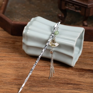 Detail of silver bamboo-shaped hair pin with green bead and fan-shaped tassel charm
