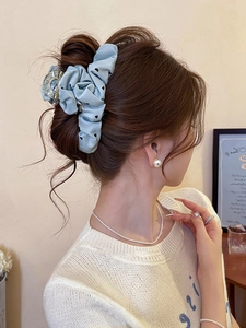 Detailed view of light blue chiffon hair scrunchie with black heart pattern on a messy bun