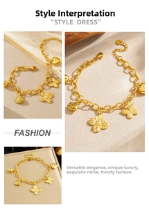 Détail d'un bracelet à chaîne dorée avec breloques papillon et cœur sur fond de pierre