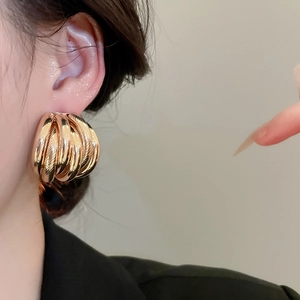 Close-up of oversized multi-layer gold-plated hoop earrings on a model for a bold style