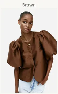 Detail of elegant brown puff sleeve blouse featuring a decorative golden vintage button