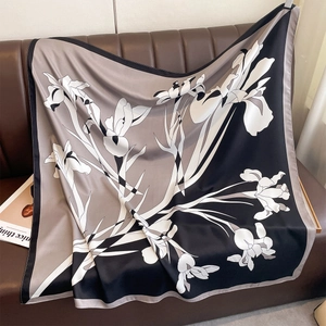 Detail of silk-feel square scarf featuring large iris print on a brown leather sofa
