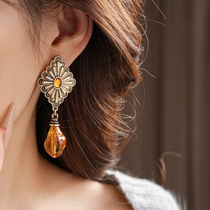 Close-up of vintage golden drop earrings with amber beads and geometric metal plates