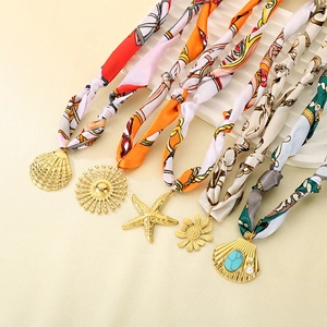 Détails macro de colliers foulards en soie dopamine avec pendentifs étoile de mer dorés