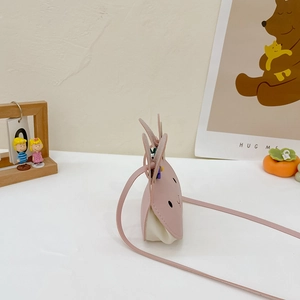 Side view of pink PU leather rabbit crossbody bag for kids on a cute decorative desk