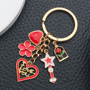 Macro shot of gold enamel keychain with red heart, star wand, and rose pendants