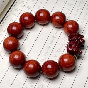 Dettaglio di perle in legno di sandalo rosso e incisione PiXiu su un bracciale in legno