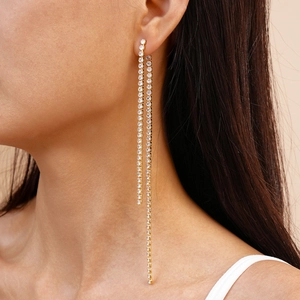 Close-up of elegant gold long tassel earrings with sparkling cubic zirconia on a model