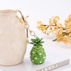 Detail of a sparkling green pineapple keychain with crystals hanging on a ceramic vase