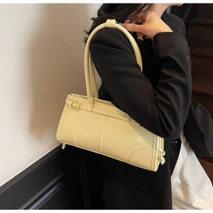 Detail view of stylish yellow leather handbag held by model in black blazer