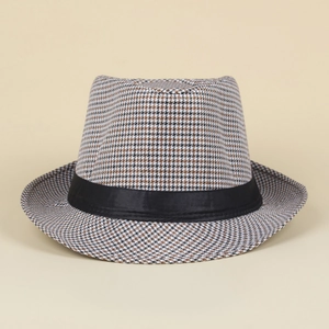 Detail of classic houndstooth jazz hat with black ribbon trim on minimalist background