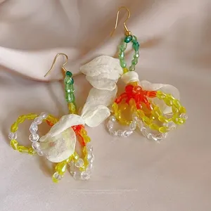 Macro detail of floral tassel earrings with colorful crystal beads and a chiffon bow