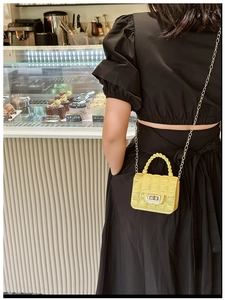 Detail of yellow quilted jelly bag with metal turn-lock closure and gold chain strap