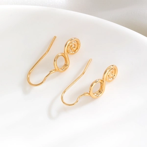 Detailed macro view of gold-tone spiral earrings featuring a polished infinity design