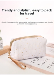 Detail of white star print makeup bag with golden zipper and wrist strap on table