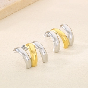 Détail macro de boucles d'oreilles C à trois couches en contraste or et argent poli