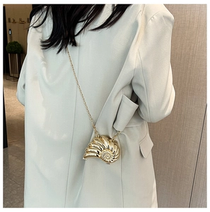 Goldene Umhängetasche in Schneckenform mit eleganter Kette auf einem weißen Blazer