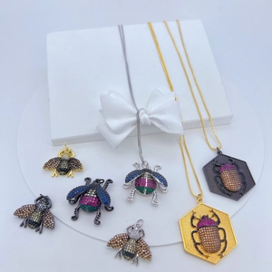Detail of copper insect pendants with micro-pave crystals in gold and black finishes