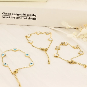 Detail of adjustable gold bracelets with evil eye, heart, and butterfly charms