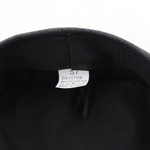 Détail intérieur d'une casquette gavroche noire avec étiquette de taille 57 et composition