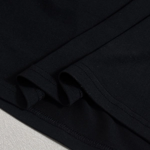 Vue détaillée du tissu en maille noire avec des coutures doubles précises sur l'ourlet