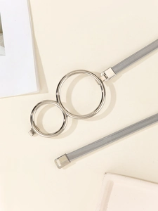 Detail of grey elastic belt with dual interlocking silver round metal buckles on beige background