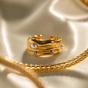 Detail of 18k gold-plated C-shaped ring with wave texture, white pearls and crystals