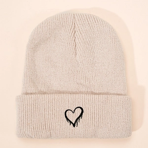 Minimalist beige knitted beanie for kids featuring a black embroidered heart pattern