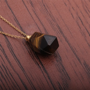 Tiger's eye gemstone perfume bottle pendant necklace with golden chain on wood