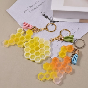 Porte-clés en résine alvéolée avec motif abeille, anneau métal et pompons en cuir coloré